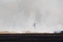 A firefighter battles a blaze on a farm next to the A11 in Cambridgeshire