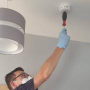 Archive: a Fire Safety team member tests a smoke alarm.