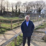 Cllr Geoffrey Sell next to the unfinished allotments and playground in Stansted Mountfitchet